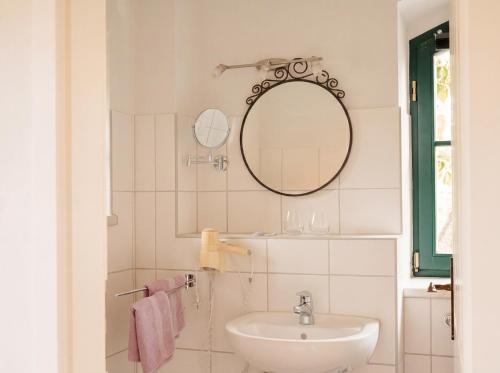 a white bathroom with a sink and a mirror at Fliederhof Stücken Apartments bei Potsdam in Michendorf
