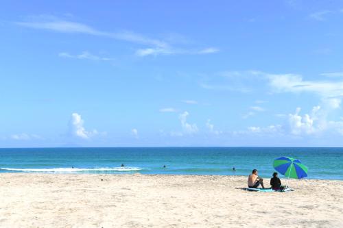 two people sitting on a beach with an umbrella at Sunny Side Cottage in Shimoda