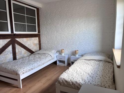 a bedroom with two beds and two windows at Za Wysokim Murem in Czarne