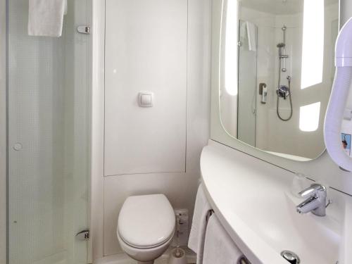 a bathroom with a toilet and a sink and a mirror at ibis Cholet in Cholet