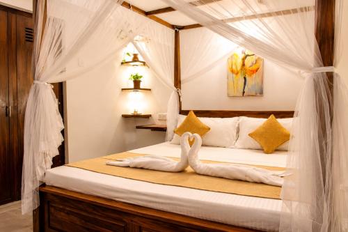 two swans sitting on a bed in a bedroom at Villa Serene Herbs Dickwella in Dickwella