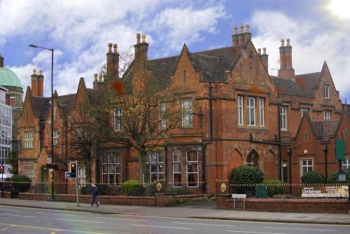 a large brick building with a person walking in front of it at Best Western Plough and Harrow Hotel in Birmingham