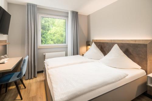 a bedroom with a bed and a desk and a window at Hotel zur Post in Hemmingen