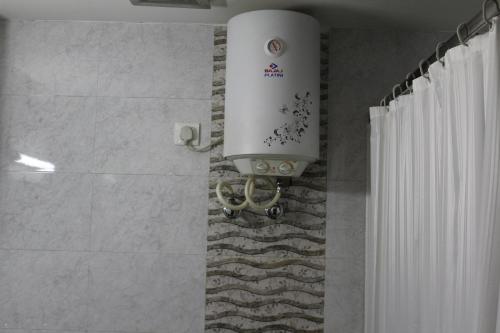 a bathroom with a shower curtain and a water tank at Hotel Angel in Greater Noida