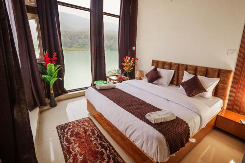 a bedroom with a large bed with a large window at hotel tripta ganga in Rishīkesh