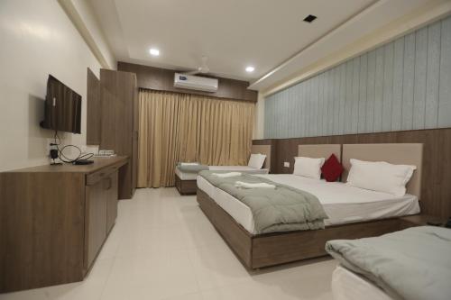 a bedroom with two beds and a television in it at Royal Palace Hotel Surat Velanja in Sāyan