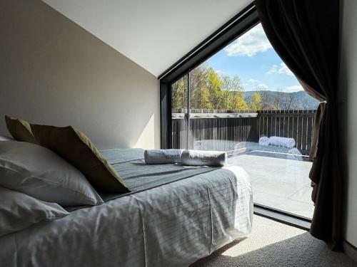 ein Schlafzimmer mit einem Bett und einem großen Fenster in der Unterkunft Apartamenty Malinka in Wisła