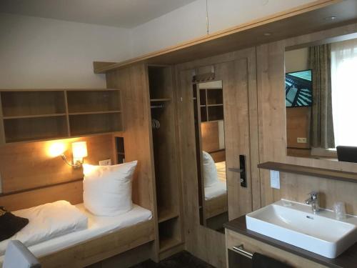a bathroom with a bed and a sink and a mirror at Landgasthof Meisel in Kalchreuth