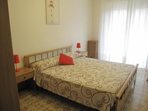 a bedroom with a bed with a red pillow on it at Appartamento Island Brioni in Grado-Pineta