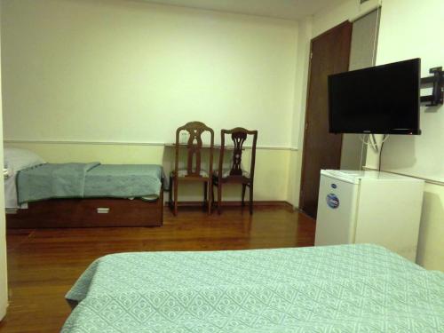 a room with two beds and a television and two chairs at Hotel Casablanca Montevideo in Montevideo