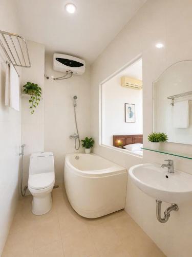 a white bathroom with a toilet and a sink at Hani Motel Da Nang in Danang