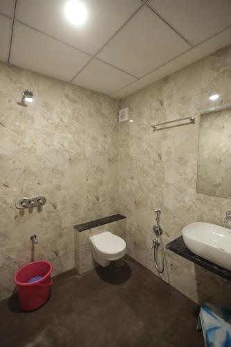 a bathroom with a toilet and a sink at Royal Palace Hotel Surat Velanja in Sāyan