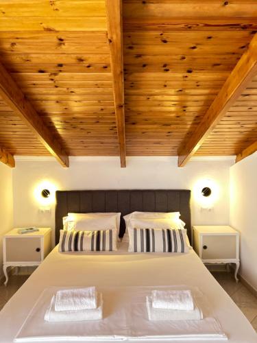 a bedroom with a large white bed with wooden ceilings at Paradises's Nest in Agios Georgios