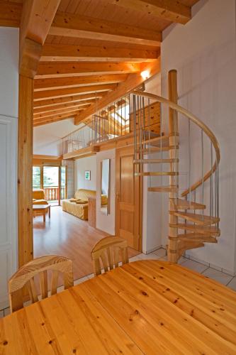 a dining room with a wooden table and a spiral staircase at Les Naturelles in Leukerbad