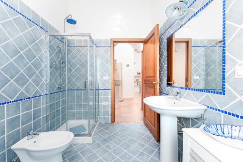 a blue tiled bathroom with a sink and a mirror at Sole in Onifai