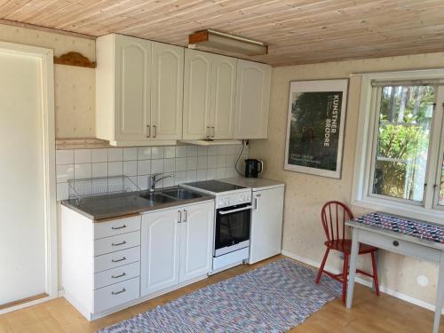 a kitchen with white cabinets and a sink and a table at Gäststuga på Tjörn in Rösselvik