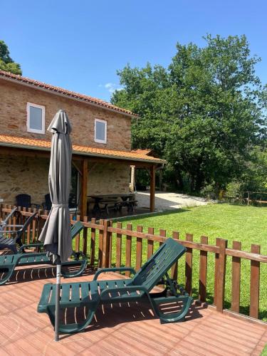 a group of lawn chairs and an umbrella on a deck at Casa do Canastro in Sever do Vouga