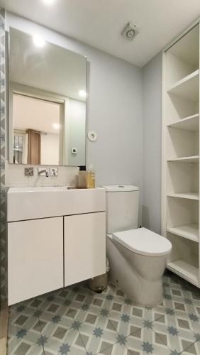 a white bathroom with a toilet and a mirror at Torrinha's Backyard in Porto