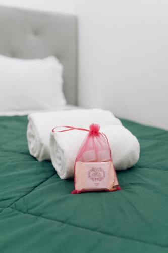 a pink bag sitting on top of a bed with towels at Encanto do Lima Guest House By Lethes Legacy in Ponte de Lima