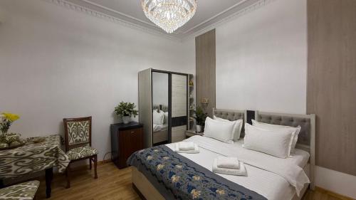 a bedroom with a bed and a chair and a chandelier at Giza Grand Hotel in Tashkent