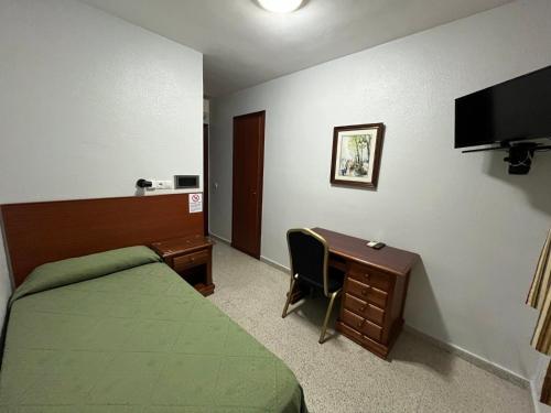 a bedroom with a bed and a desk and a desk at Hostal Blumen in Algeciras