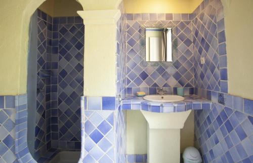 a blue tiled bathroom with a sink and a mirror at Gîte au calme l'eclaircie in Régusse