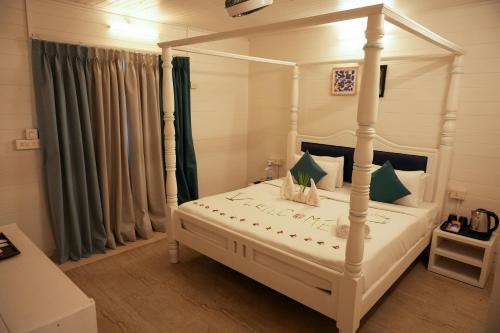 a bedroom with a white canopy bed with green curtains at Royal Bishnu in Calangute