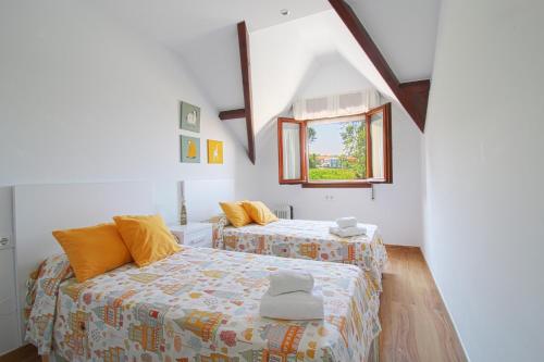 a bedroom with two beds and a window at Apartamento Arena Dorada in Somo
