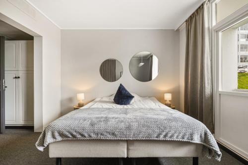 a bedroom with a bed with two mirrors on the wall at A11 Apartments in Ålesund