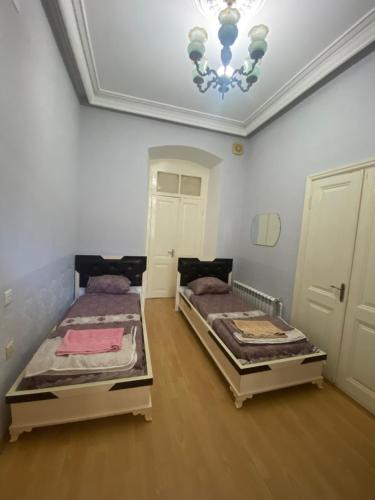 two beds in a room with a chandelier at Beaming_House in Sheki