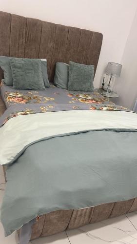 a large bed with a brown headboard with leaves on it at THE TIMES HOUSE, Toit panoramique vue mer & groupe électrogène in Libreville