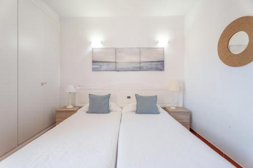 a bedroom with a white bed with blue pillows at Casa Perla in Playa de Santiago