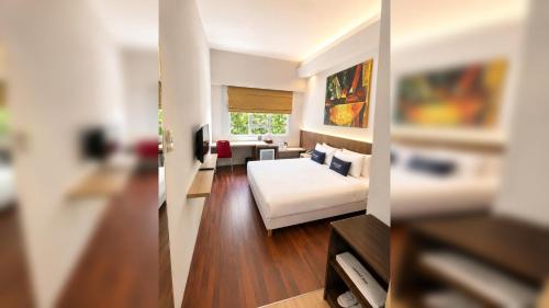 a bedroom with a bed and a living room at Kyriad Arra Hotel Cepu in Cepu