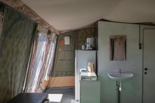 a small bathroom with a sink and a refrigerator at Glamlodge Ameland direct aan het strand in Nes