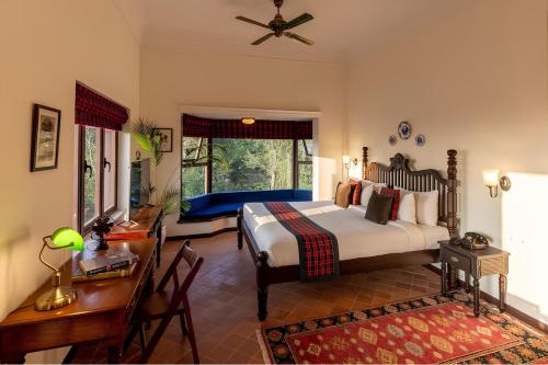 a bedroom with a bed and a table and a desk at Old Kent Estates & Spa, Coorg in Suntikoppa