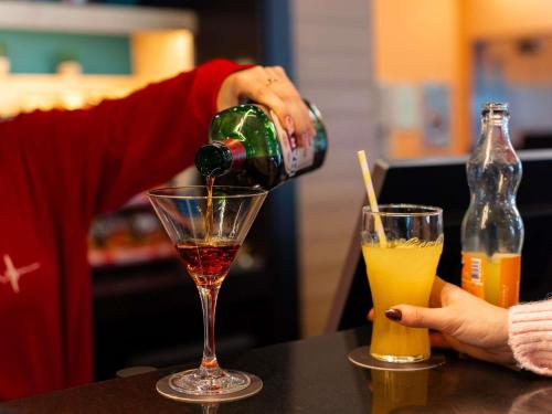 a person pouring a drink into a martini glass at Ibis Ripollet in Ripollet