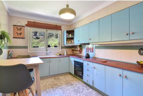 a large kitchen with blue cabinets and a table at Begur "Casa es Pou" in Begur