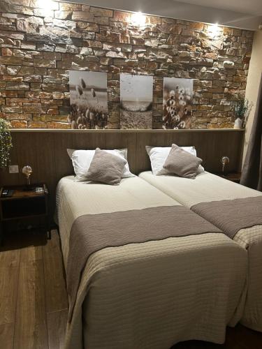 two beds in a bedroom with a brick wall at Chambre d'hôtes de la Riaille 400 m de la dolce via in Le Cheylard