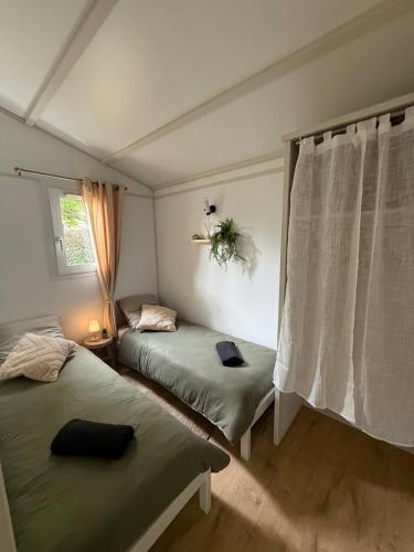 a room with two beds and a window with a curtain at Charmant chalet près d Albi et des vignobles in Rivières