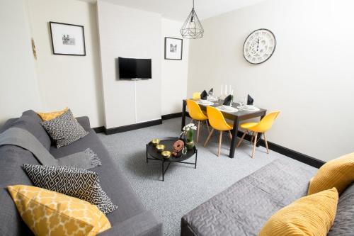 a living room with a couch and a table with yellow chairs at Wherstead House in Ipswich