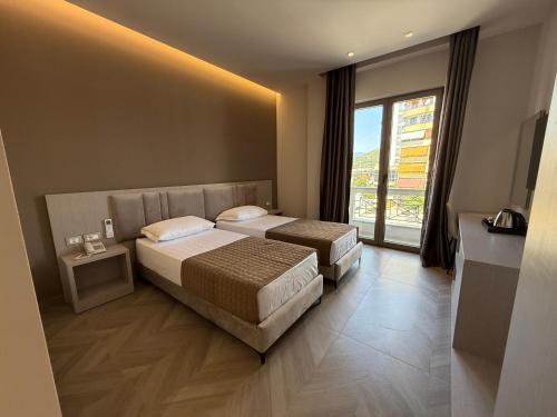 a hotel room with two beds and a window at Rodi Hotel Elbasan in Elbasan
