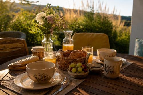 a wooden table with a breakfast of bread and juice at La Bergerie de Losse in Traize