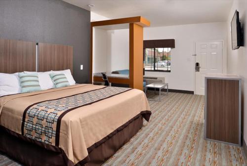 a hotel room with a large bed and a television at Scottish Inn & Suites - Conroe in Conroe