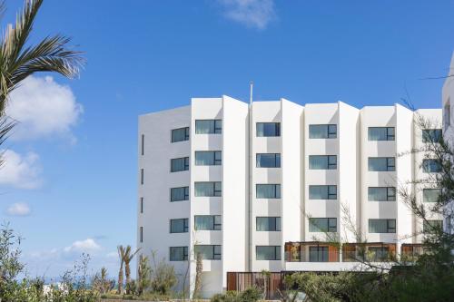a white building with a palm tree in front of it at Idou Malabata Beach and SPA in Tangier