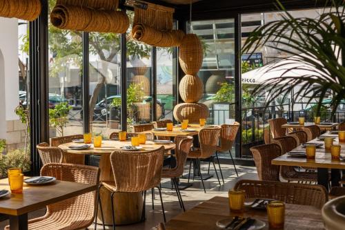 ein Restaurant mit Holztischen und -stühlen und Fenstern in der Unterkunft Hotel Baltum in Albufeira