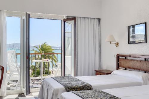 a hotel room with two beds and a balcony at Hotel Sis Pins in Port de Pollensa