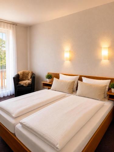 ein großes weißes Bett in einem Zimmer mit einem Stuhl in der Unterkunft Hotel Daheim in Gehlberg