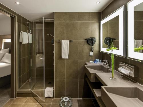 a bathroom with two sinks and a shower at Novotel Hannover in Hannover
