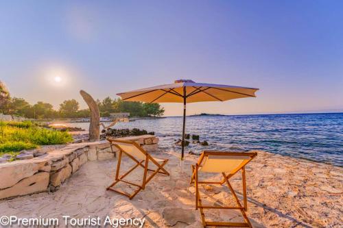 a couple of chairs and an umbrella on a beach at Hidden Beach Villa Biankura in Smokvica