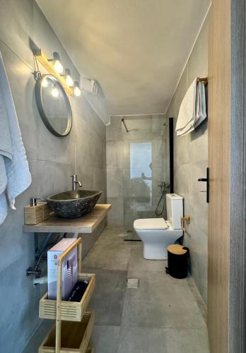 a bathroom with a sink and a toilet and a mirror at Salty Rock - Kythnos Suite in Kithnos